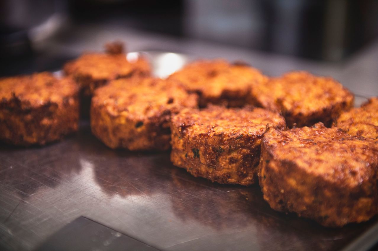 Nahaufnahme von goldbraunen, knusprigen gebratenen Pasteten auf einer Metalloberfläche, möglicherweise in einer Restaurantküche.