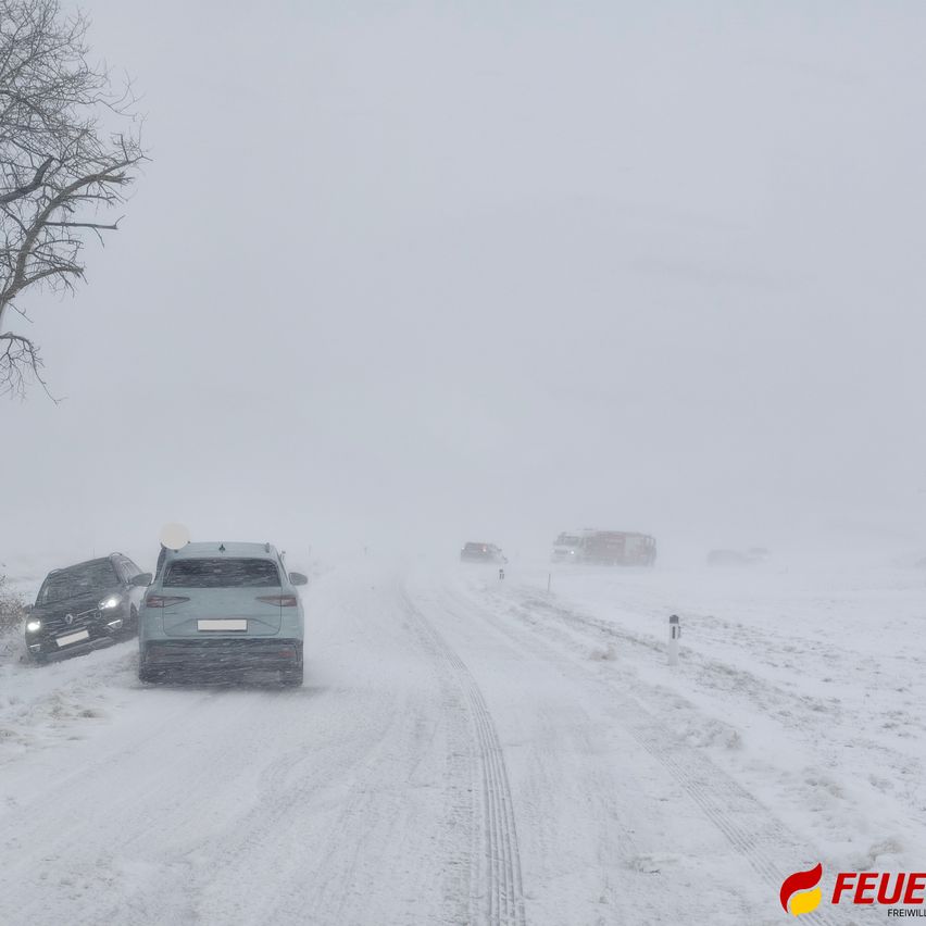 Schwerer Schneefall hat das Reisen erschwert. Zwei Autos sind im Schnee stecken geblieben, und ein Feuerwehrwagen nähert sich.