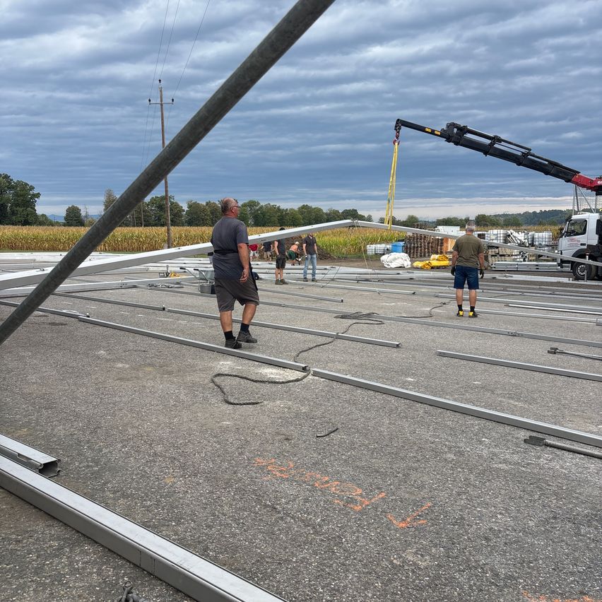 A group of workers are installing metal beams on a construction site under a cloudy sky.