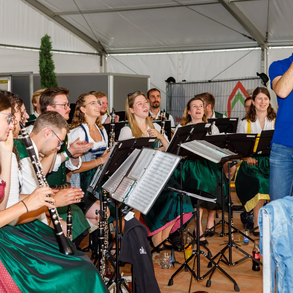 Eine Gruppe von Menschen führt ein Musikkonzert in einem Zelt durch.