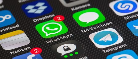Eine Nahaufnahme eines Smartphone-Bildschirms mit verschiedenen App-Symbolen, einschließlich WhatsApp, Facebook und Dropbox. WhatsApp hat eine Benachrichtigungsanzahl von 2.