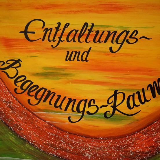 Ein künstlerisches Poster mit Sonnenuntergangshintergrund zeigt die Worte 'Entfaltungs- und Beginnungs-Raum' in fetter, schwarzer Schrift. Die Farben sind warm und gehen von Gelb zu Orange über. Das Design ist lebendig und abstrakt.