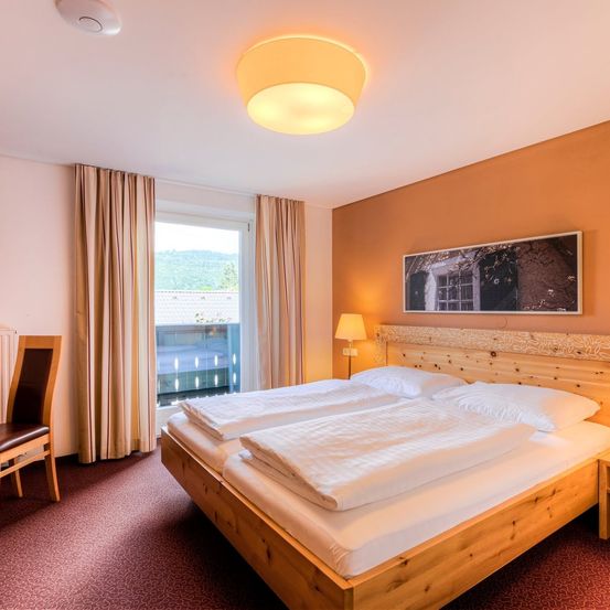 Ein gemütliches Schlafzimmer mit zwei Betten, einer Lampe und einem Fenster mit Blick auf das Freie.
