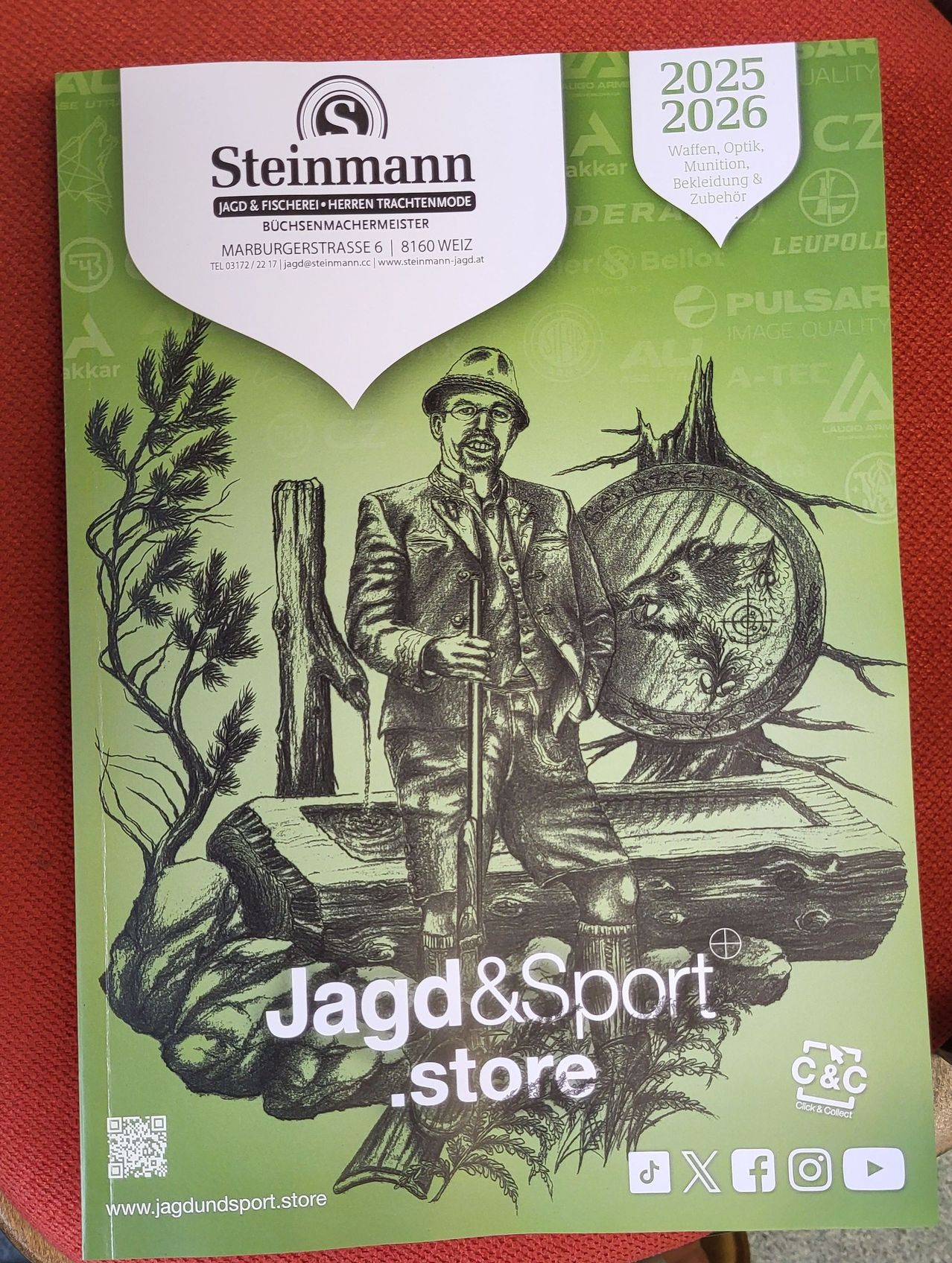 Grüner Umschlag einer Zeitschrift mit dem Titel Jagd & Sport Store, auf dem ein lächelnder Mann in einem Hut mit einem Stock abgebildet ist.