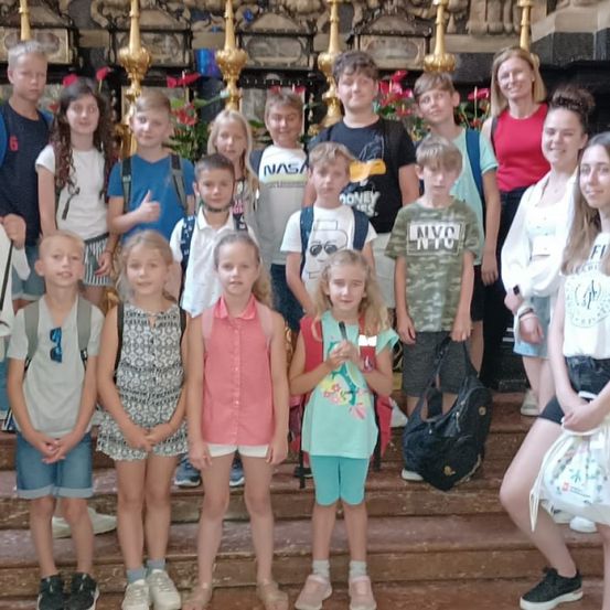 Eine Gruppe von Kindern und zwei erwachsenen Frauen posiert auf den Stufen einer Kirche.