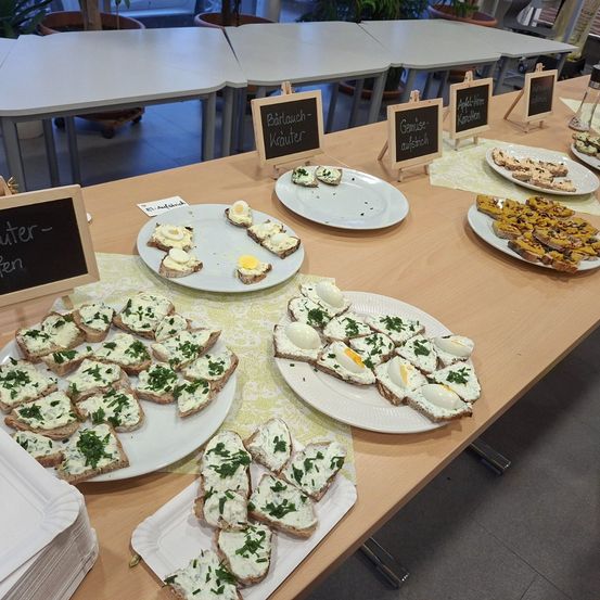 Ein Tisch mit verschiedenen Tellern mit Essen, einschließlich Toast mit Toppings, Eiern und anderen Gerichten. Jeder Teller hat ein Etikett mit seinem Namen.
