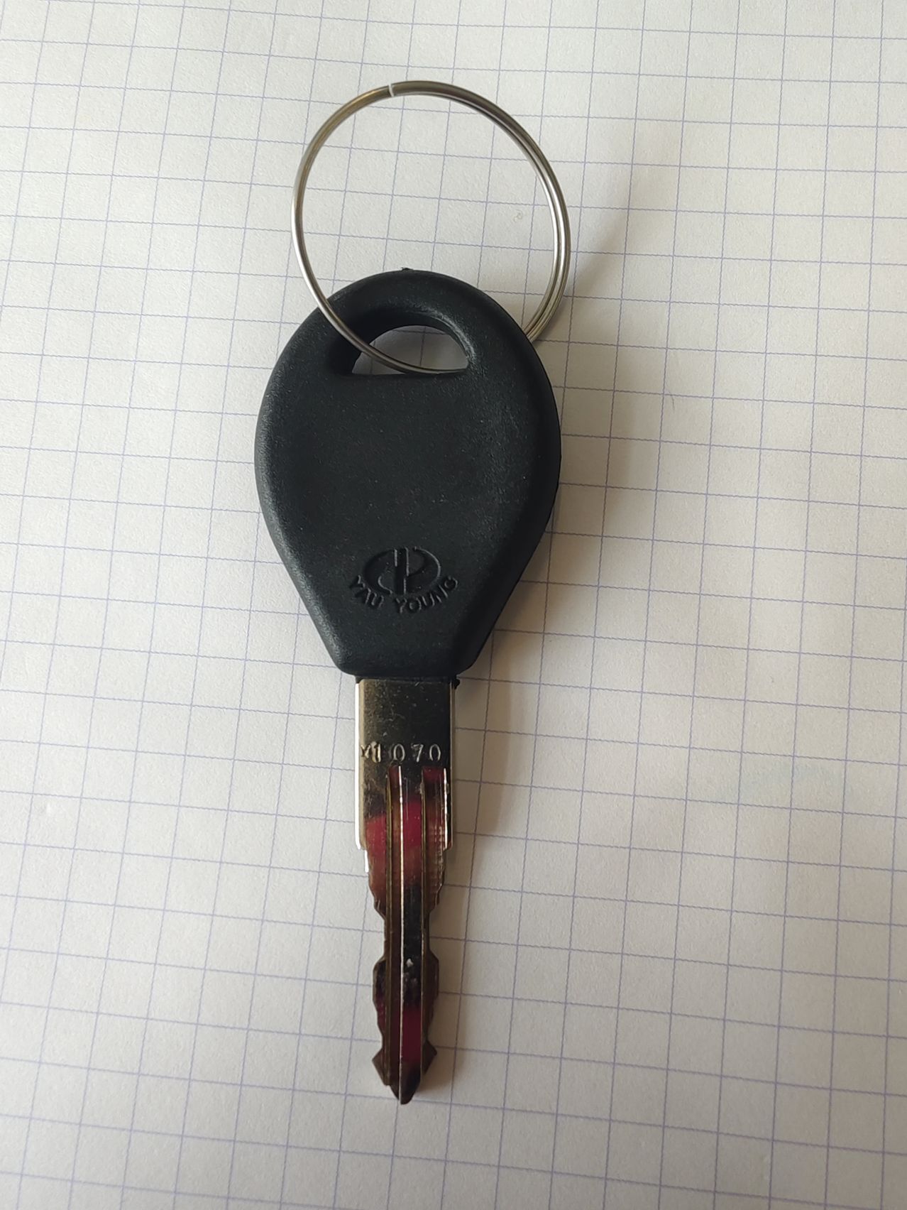 Ein schwarzer Hyundai-Schlüssel mit einem silbernen Schlüsselring auf einem gepunkteten Papierhintergrund.