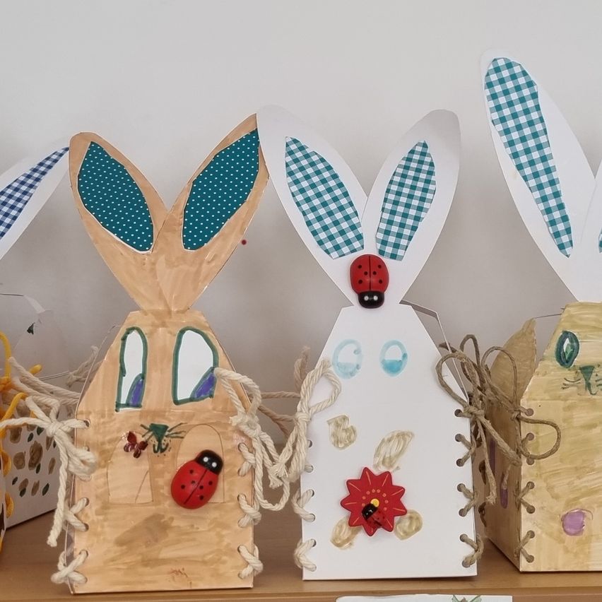 Fünf handgefertigte Kaninchen-förmige Boxen mit verschiedenen Dekorationen werden auf einer Holzoberfläche ausgestellt. Jede Box hat einzigartige Merkmale, einschließlich Marienkäfer und Blumen. Sie sind zum Halten von Gegenständen konzipiert und scheinen handgemacht zu sein.