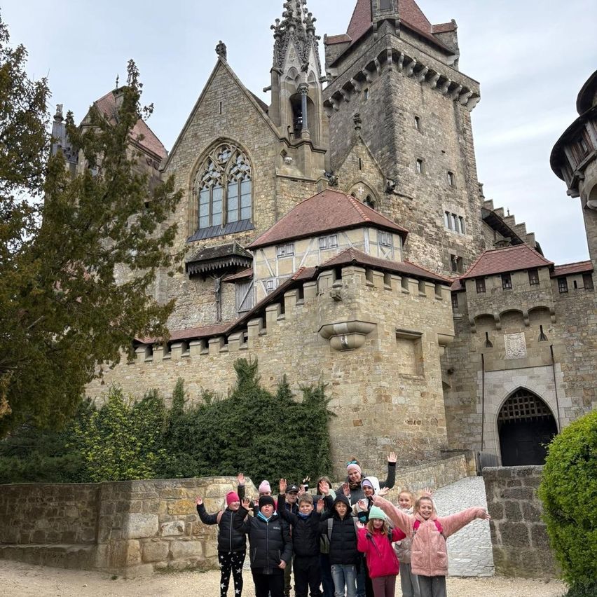 Eine Gruppe von Menschen in Winterkleidung posiert für ein Foto vor einer großen Steinburg mit einem hohen Turm.
