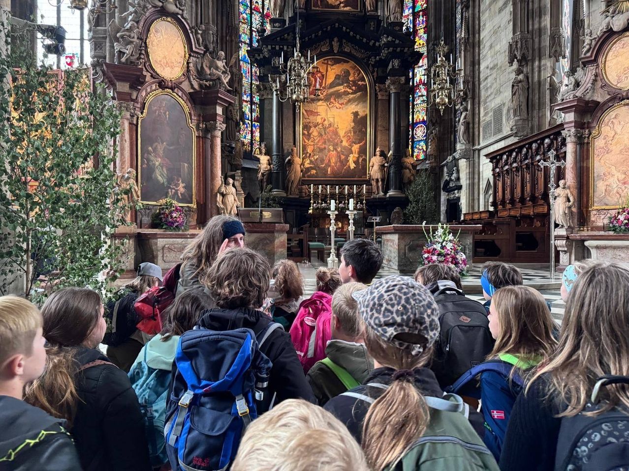 Eine Gruppe von Menschen mit Rucksäcken steht in einer Kirche und sieht ein Gemälde auf dem Altar.