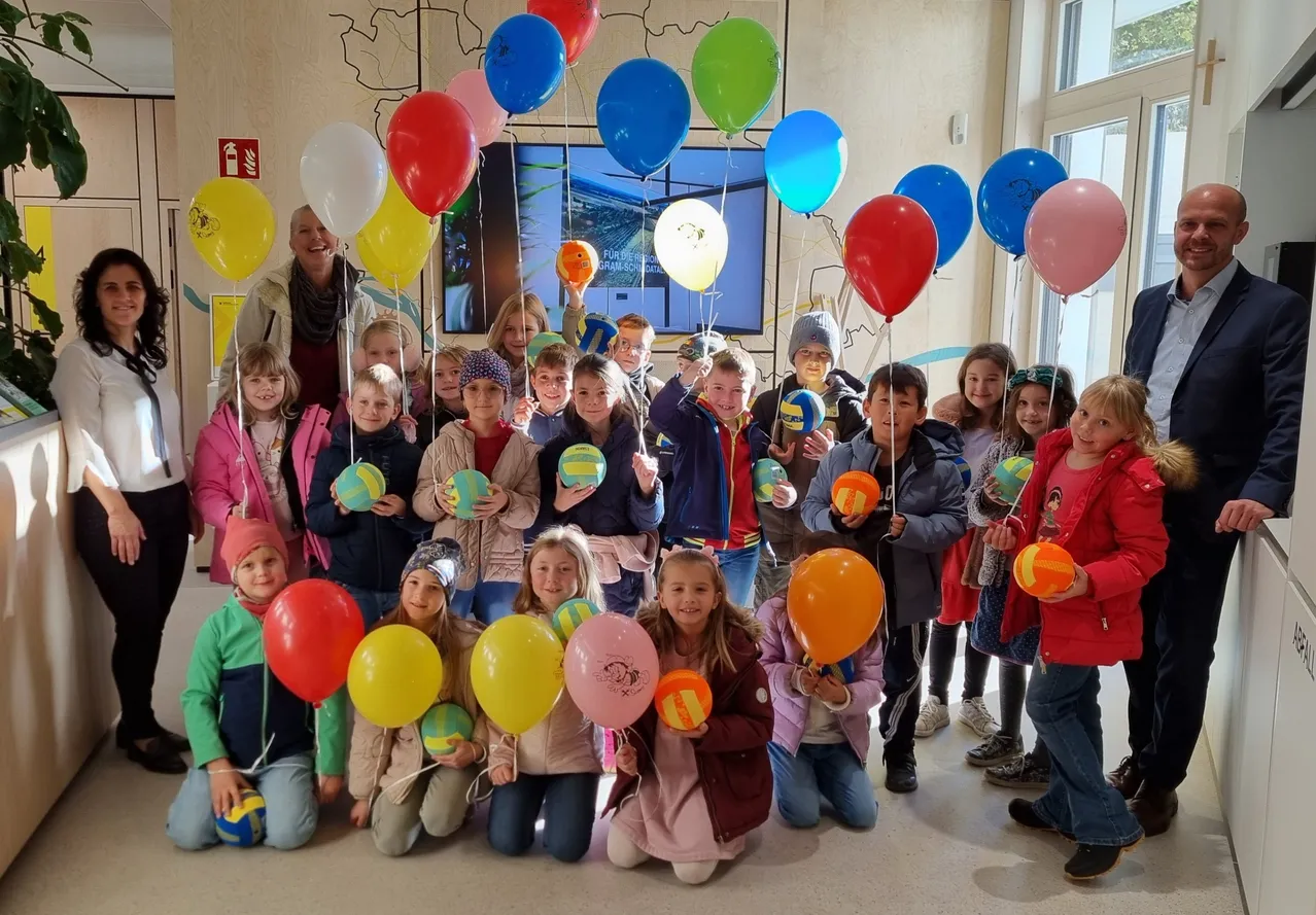 Eine Gruppe von Kindern und Erwachsenen posiert für ein Foto, während sie bunte Luftballons halten.