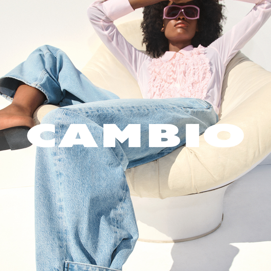 Eine Frau in blauer Jeans und rosa Bluse sitzt auf einem weißen Sitzsack mit dem Kopf auf der Hand. Das Wort 'CAMBIO' ist prominent in Weiß dargestellt.
