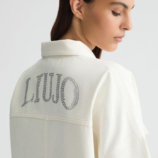 Eine Frau trägt eine weiße Jacke mit dem Wort 'LIU JO' in Silber auf dem Rücken geschrieben.