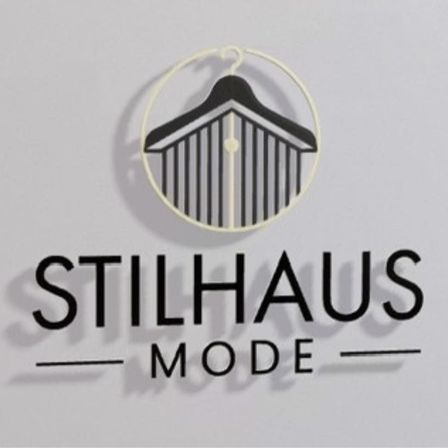 Das Logo von Stilhaus Mode, mit einem schwarzen Kleiderbügel in einer kreisförmigen Form, wird auf einem weißen Hintergrund gezeigt.
