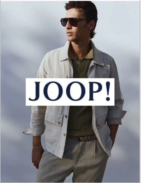 Ein Mann in einer hellen Jacke, Sonnenbrille und einem grünen Shirt posiert für ein Foto mit dem Wort JOOP! im Vordergrund.