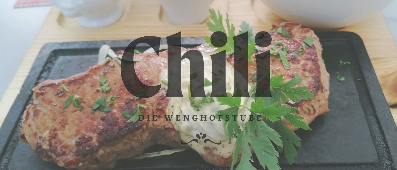 A close-up of a dish with meat, cheese, and parsley on a wooden surface with the word 'Chili' in bold letters.