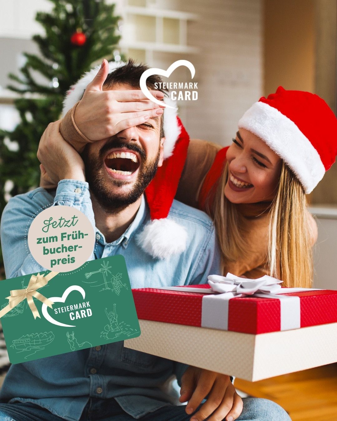 Ein Mann und eine Frau in Weihnachtsmützen halten eine Geschenkbox. Der Mann sieht überrascht aus, während die Frau lächelt. Sie stehen vor einem Weihnachtsbaum. Die Geschenkbox hat ein Band und eine Karte mit dem Text 'Jetzt zum Frühbucher-preis'.