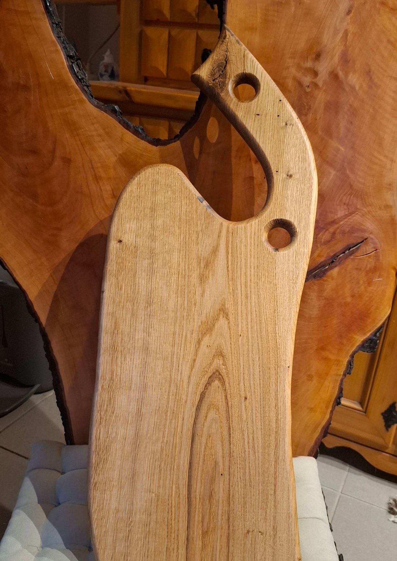 Ein Holzschneidebrett mit drei Löchern, vor einem hölzernen Schrank mit einem offenen Abschnitt positioniert.