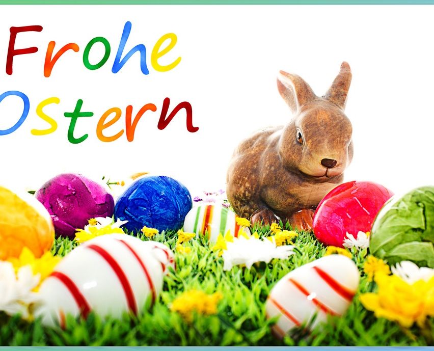 Eine Osterkarte mit einem Hasen und verschiedenen farbigen Eiern auf einem Rasen mit Blumen.