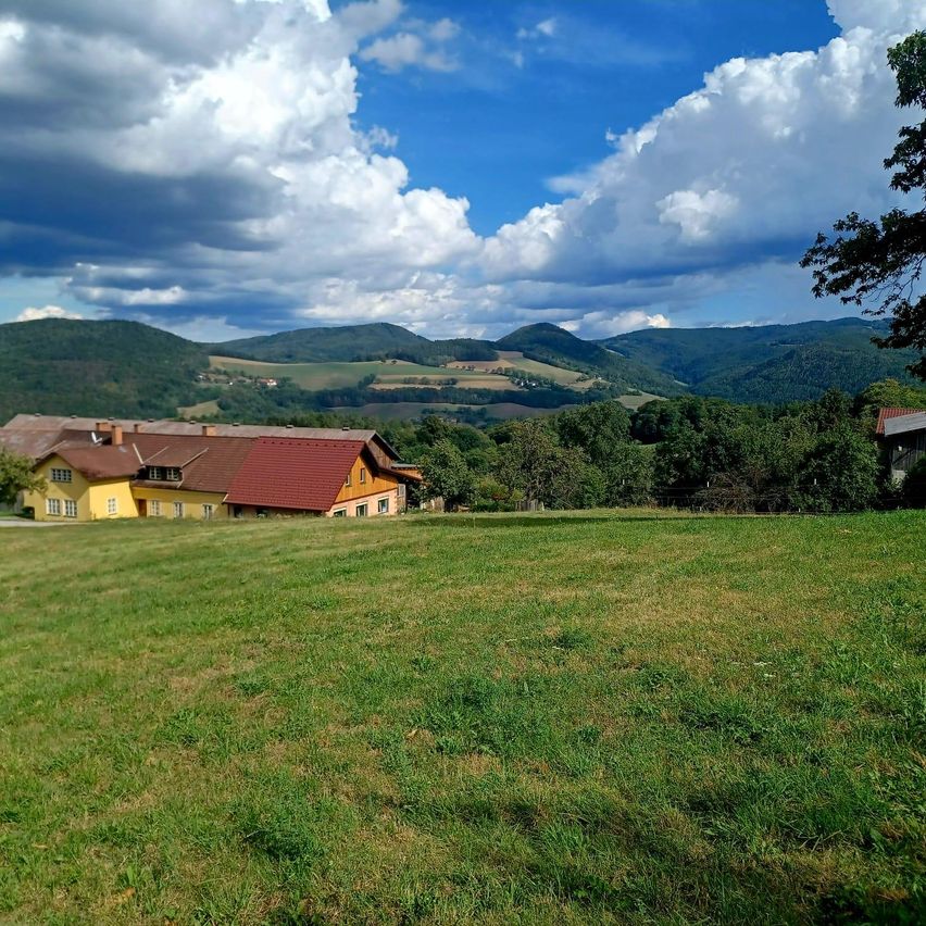 Bauernhaus in hügeliger Landschaft mit Wolken am Himmel