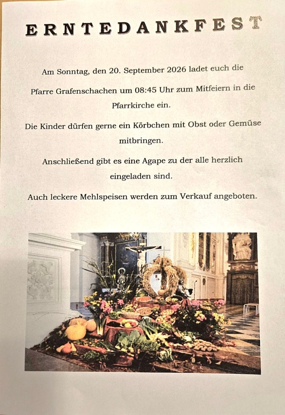 Ein Kircheninneres mit einem Altar, geschmückt mit Blumen, Früchten und Gemüse. Ein Kreuz ist an der Wand über dem Altar angebracht.