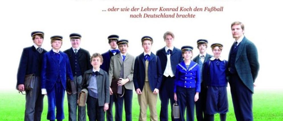 Poster für den Film 'Der ganz grosse Traum' mit einer Gruppe von Kindern und einem Lehrer auf einem grünen Feld.