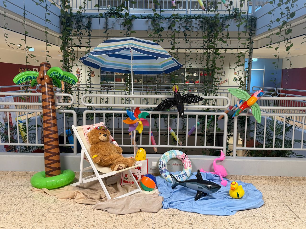 Ein Ruhebereich mit Stuhl, Regenschirm und Poolauftrieb. Ein Teddybär sitzt auf dem Stuhl. Ein Rettungsring und ein Hai-Auftrieb sind in der Nähe.