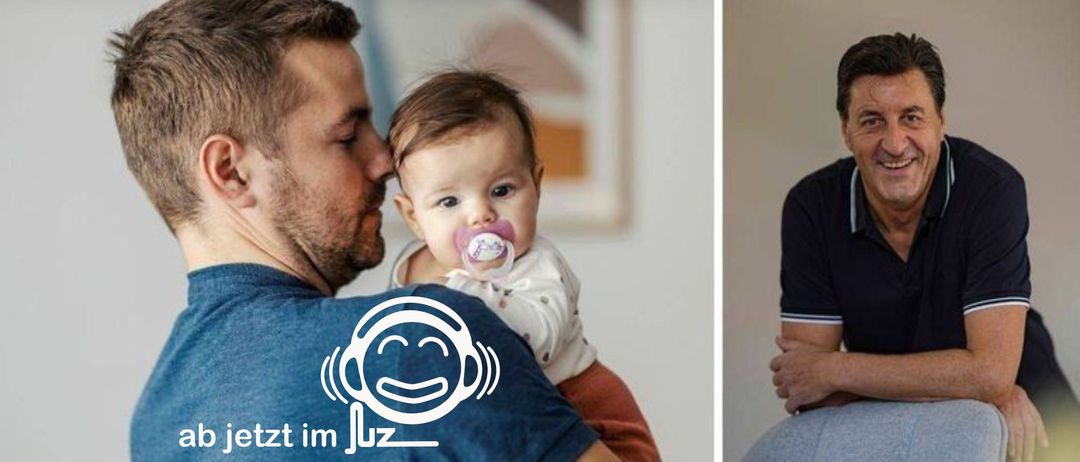 Ein Mann mit Kopfhörern hält ein Baby mit einem Schnuller im Mund. Das Baby schaut direkt in die Kamera.