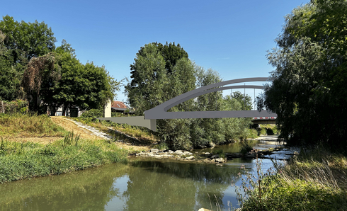 Eine graue Bogenbrücke überspannt einen Fluss, umgeben von üppigem Grün und Bäumen auf beiden Seiten unter einem klaren blauen Himmel.