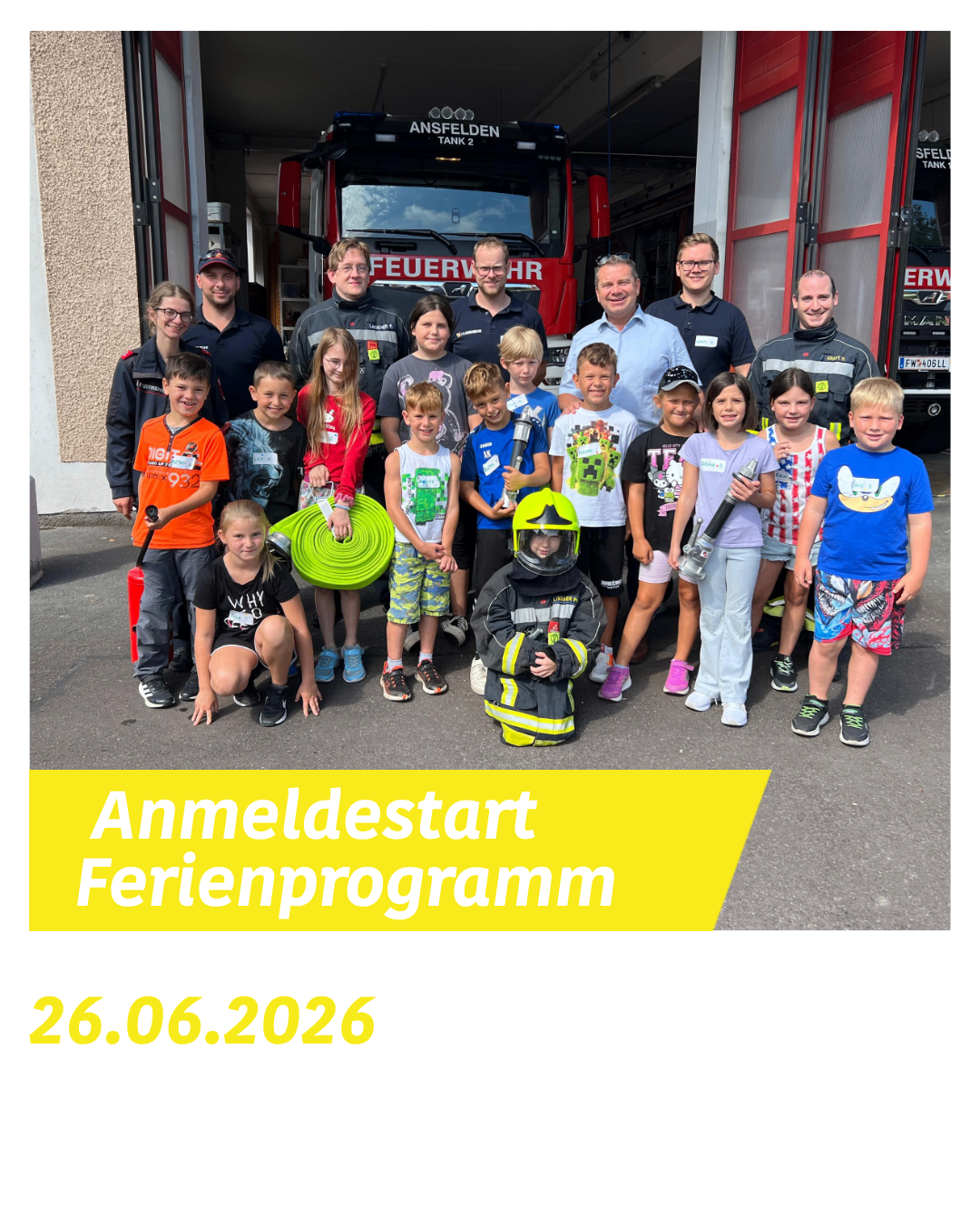 Eine Gruppe von Kindern und Erwachsenen posiert vor einem Feuerwehrauto. Ein Feuerwehrmann in der Mitte trägt einen Helm. Die Kinder tragen verschieden farbige T-Shirts. Ein gelber Banner mit den Worten 'Anmeldestart Ferienprogramm 26.06.2026' befindet sich unten links.
