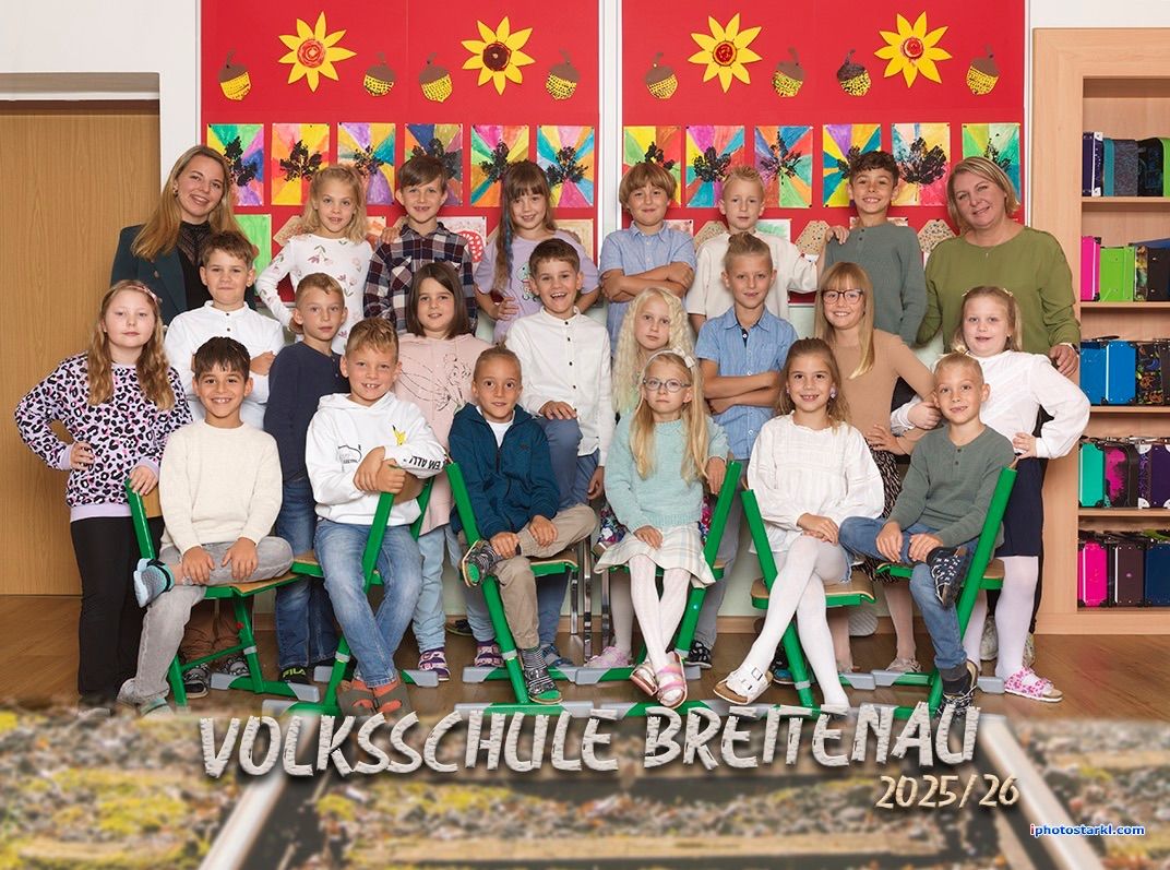 Gruppenfoto von Schülern und Lehrern der Volksschule Brettenau, aufgenommen in 2025/26. Die Kinder sitzen auf grünen Stühlen mit Sonnenblumen und Blättern, die auf einer roten Wand im Hintergrund gemalt sind.