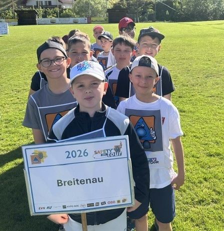 Eine Gruppe junger Jungen in Sportuniformen steht auf einem Rasenfeld, einer hält ein Schild mit der Aufschrift Breitenau 2026.