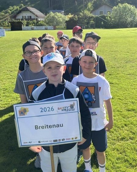 Eine Gruppe junger Jungen in Sportuniformen steht auf einem Rasenfeld, einer hält ein Schild mit der Aufschrift Breitenau 2026.