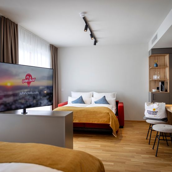 Bild enthält, Interior Design, Floor, Flooring, Home Decor, Screen, Corner, Monitor, Cushion, Furniture, Living Room