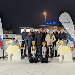 Gruppenfoto bei Nacht vor dem Thaypark, mit Personen in Winterkleidung, Pinguin-Ausschnitten und Bannern.