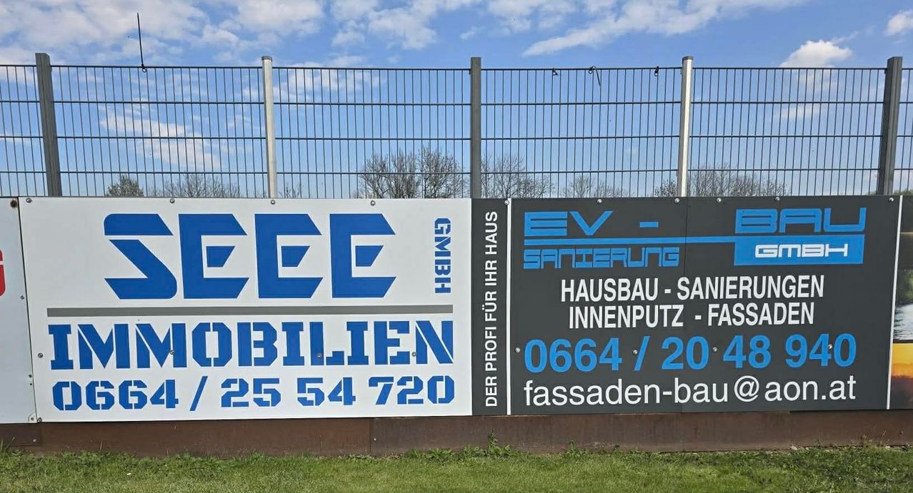Zwei Banner an einem Zaun zeigen Firmennamen und Kontaktdaten. Das erste Banner zeigt EEE Mobilien mit einer Telefonnummer. Das zweite Banner lautet EV Sanierung und bietet Hausdienstleistungen an, ebenfalls mit einer Telefonnummer.
