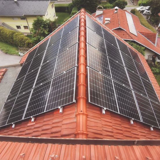 Luftaufnahme eines Hauses mit einem Solaranlagensystem auf dem Dach, bestehend aus mehreren Reihen von Solarmodulen.