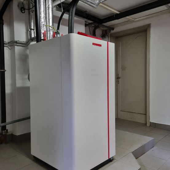 Ein großes weißes Gerät mit rotem Streifen in einem Raum mit weißer Tür und gefliestem Boden.