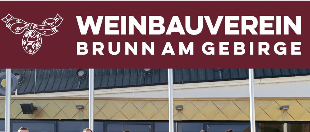 Eine Gruppe von Menschen in roten Hemden und mit Flaschen posiert für ein Foto vor einem Gebäude am 9. April 2026. Das Bild ist für eine Weinpräsentation.