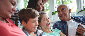 Eine vierköpfige Familie nutzt elektronische Geräte, lächelt und schaut auf ein Tablet. Das Bild hat einen grünen Rand und den Text 'Gemeinsam verbunden. Das regionale Glasfasernetz'.