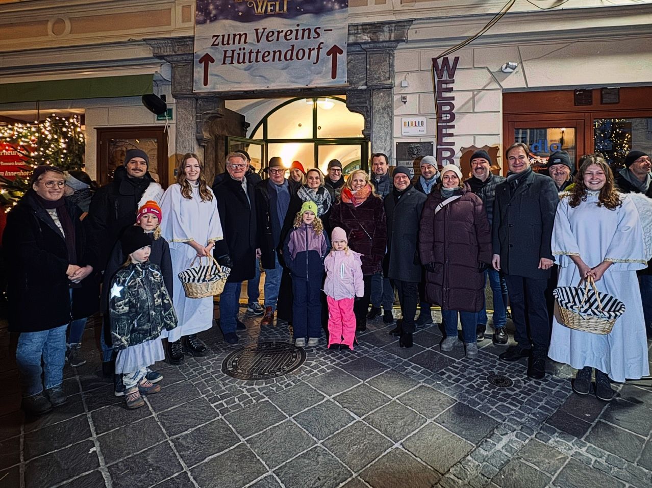 Eine Gruppe von Menschen steht vor einem Gebäude, einige mit Körben, wahrscheinlich zur Feier eines Feiertags.