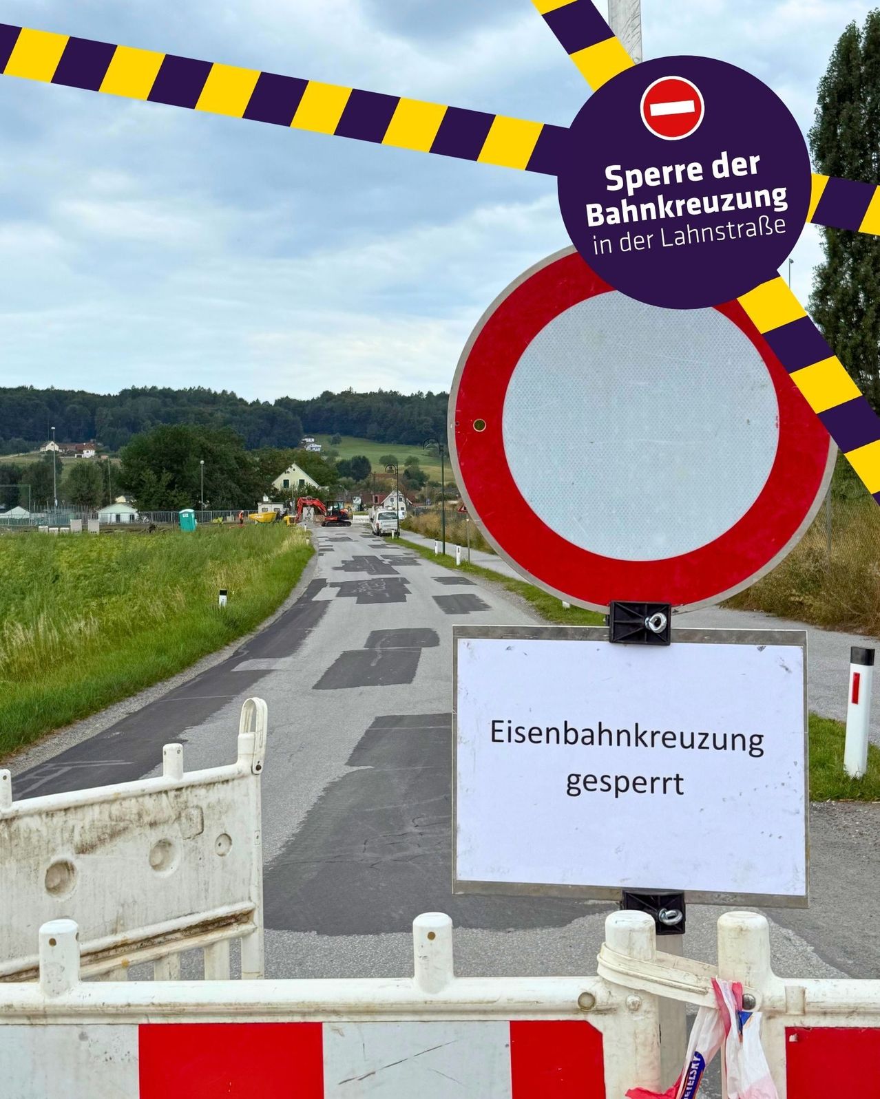 Eine Straße mit einem geschlossenen Bahnübergangsschild, einem geschlossenen Schild und einem runden rot-weißen Schild mit einem violetten Kreis oben.