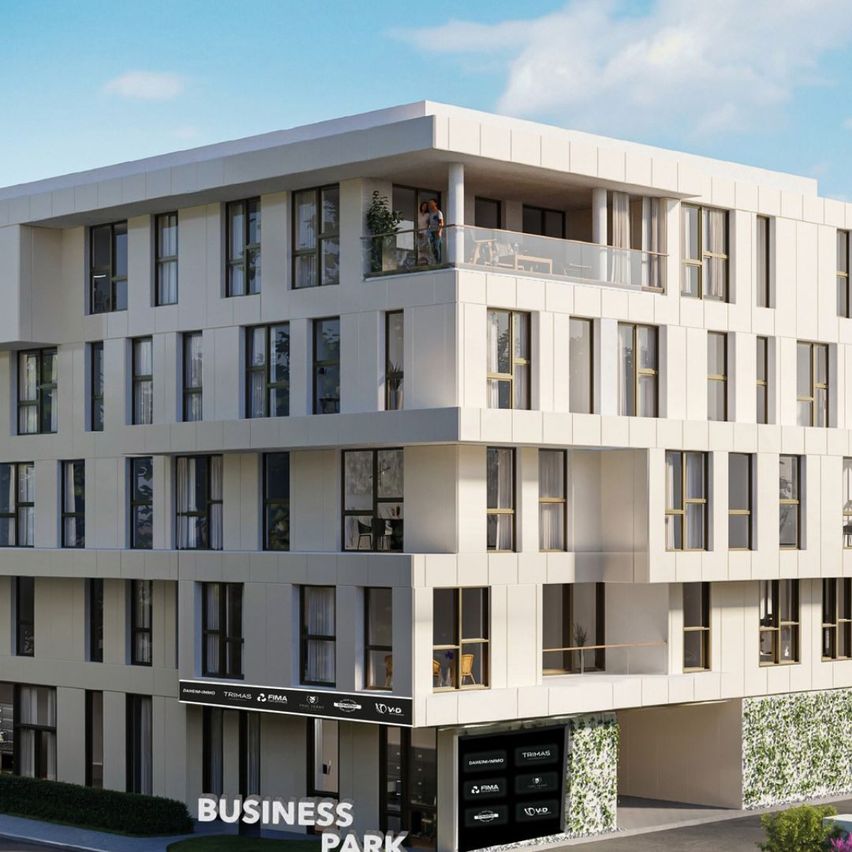 A modern white building with multiple floors, 'Business Park' sign at the bottom, a balcony with a person on the upper floor, windows with curtains, and a small garden on the side.