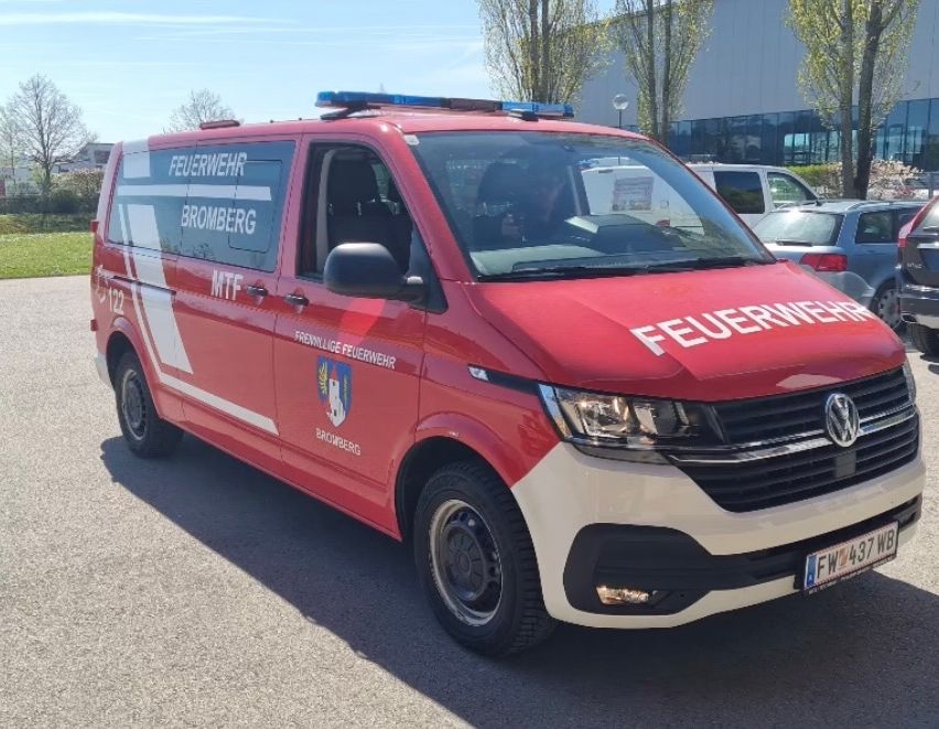 A red fire truck from Bromberg is parked outdoors, with other vehicles in the background. The truck has a blue light on top and the text 'FEUERWEHR' on the front.