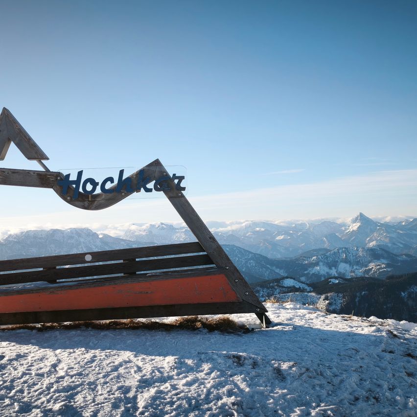 Ein Holzschild mit dem Wort Hochkar steht auf einer verschneiten Bergkette.