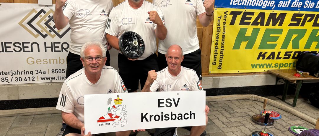 Five men in white uniforms and glasses pose for a photo in front of a wooden wall with a scoreboard and banners. They are holding a trophy and a sign that reads 'ESV Kroisbach'.