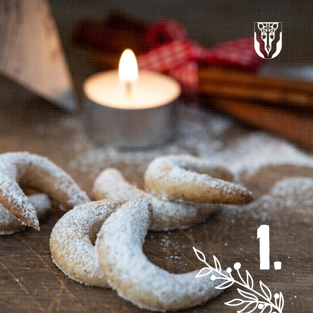 Eine Nahaufnahme von mit Puderzucker überzogenen Brezeln liegt auf einem Holztisch. Eine brennende Kerze und Zimtstangen im Hintergrund. Ein unscharfes Logo befindet sich auf der rechten Seite.
