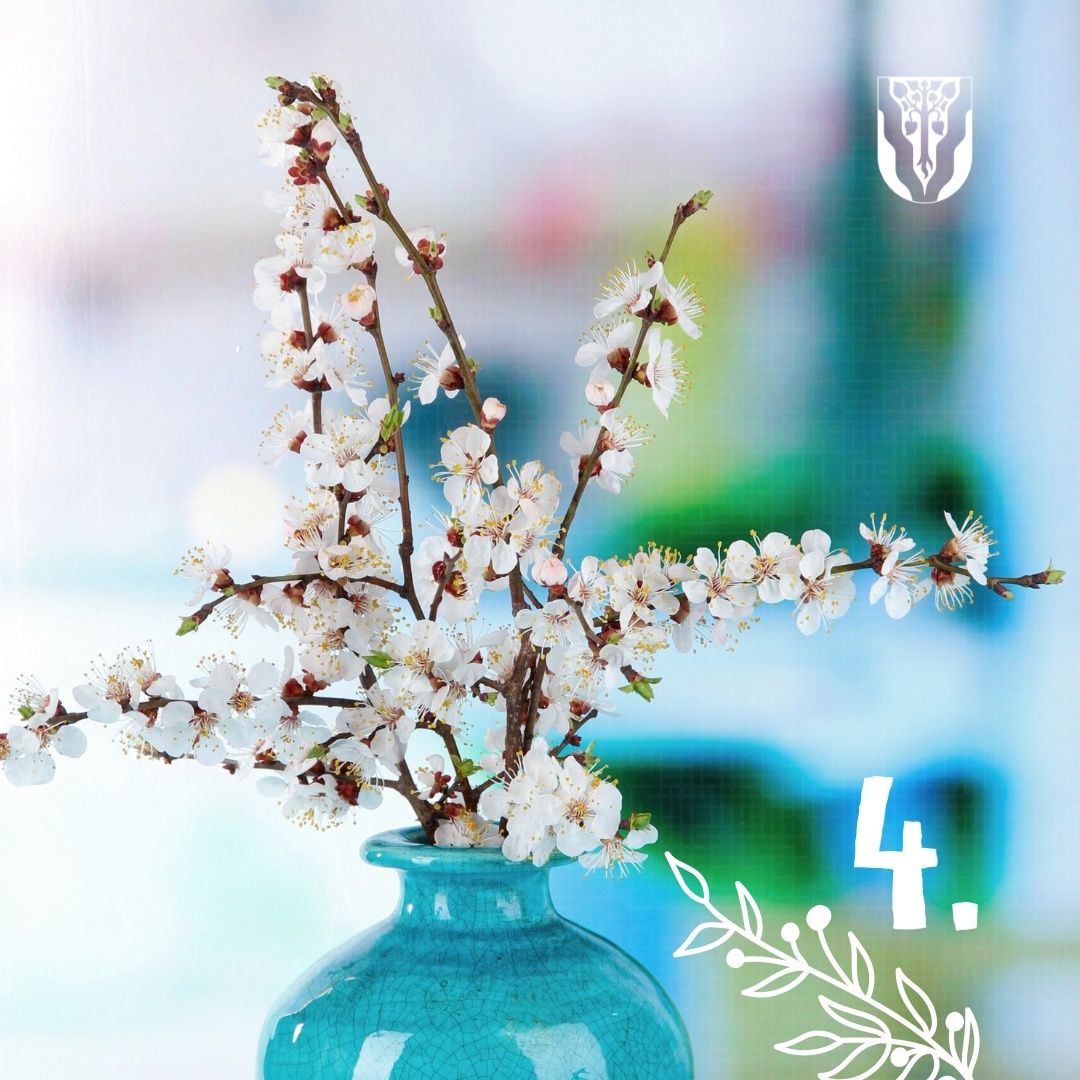 Ein Nahaufnahme einer Vase mit weißen Blumen und einer Nummer vier neben ihr. Die Vase ist blau.