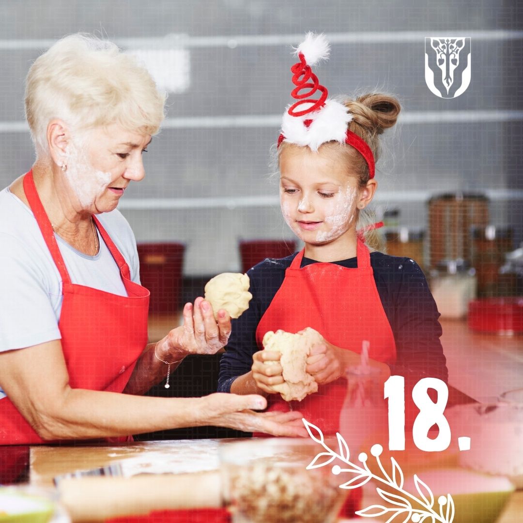 Eine ältere Frau und ein junges Mädchen in roten Schürzen backen in der Küche. Das Mädchen hat Mehl im Gesicht. Ein Wasserzeichen mit der Nummer 18 ist auf dem Bild.