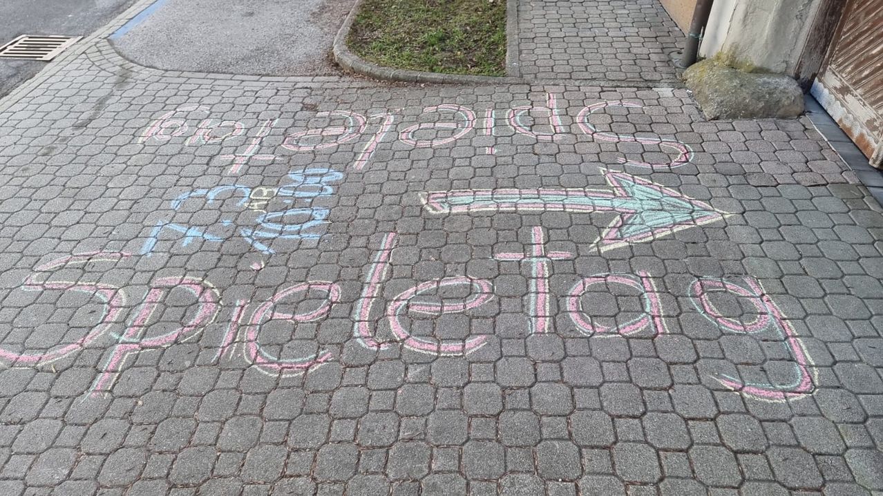 Ein Gehweg mit Kreideschrift, die 'Happy Birthday' und 'Lösche' darauf steht. Die Kreide ist in verschiedenen Farben und es gibt einen Rasenbereich an der Seite.